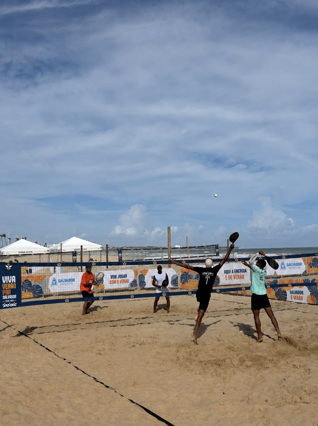 Vista lateral de quadra de areia com comunicação da marca no tapume